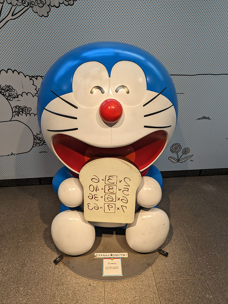 Doraemon is eating a special bread that will help him remember everything (a common wish for every student). This statue is inside the Noborito Station (in suburban Tokyo) near the Fujiko F. Fujio Museum.