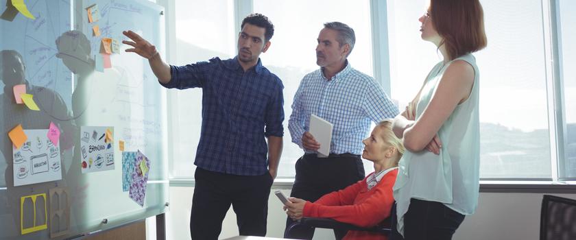 Two men pointing at a white board in an office